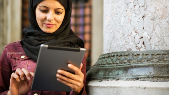 A lady in a hijab holds a tablet device 