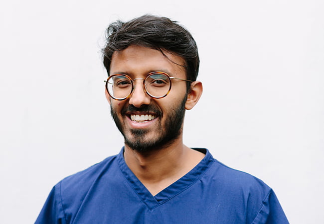 Affiliate Membership Ad 650X450 A young male dentist with glasses and blue scrubs smiling into the camera