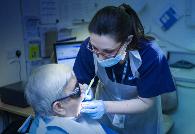 A female NHS dentist examining an elderly patient 