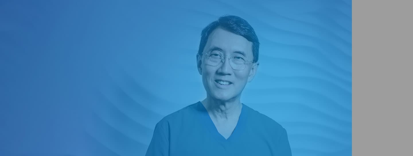 Patient Care ADVICE Standard Header 1440X545px A male dentist wearing scrubs smiling into the camera