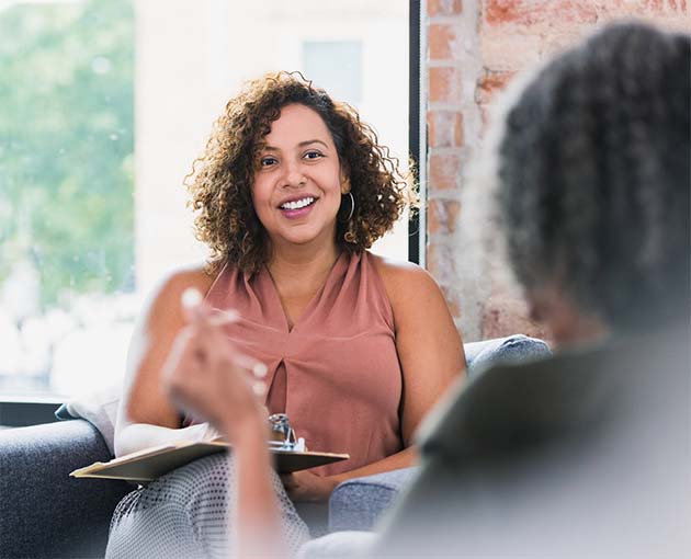 Two women seated in a bright room engaged in conversation
